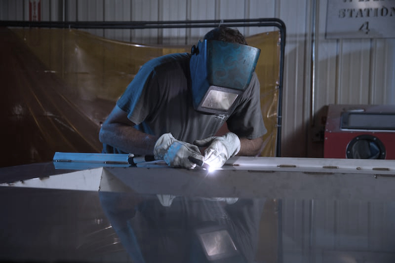 ProFab employee welding a piece of food processing equipment for installation
